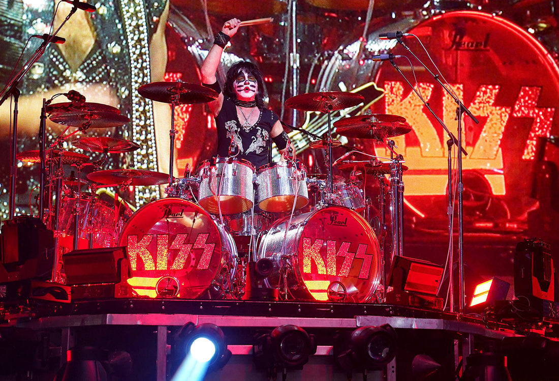 Eric Singer of KISS performing behind a large red-lit Pearl drum kit in his Catman makeup