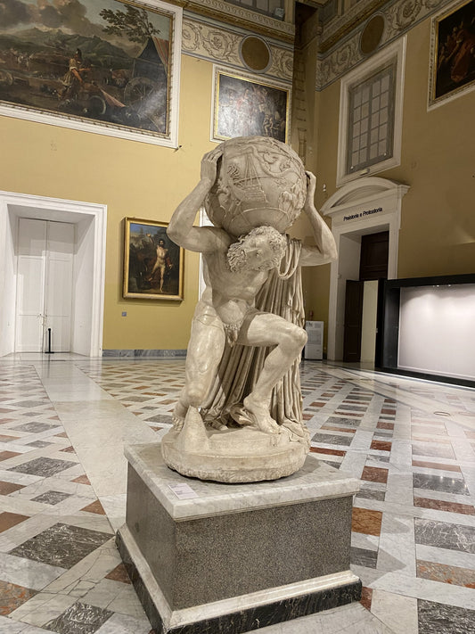 Roman marble statue of the Titan Atlas kneeling beneath a celestial globe in a museum