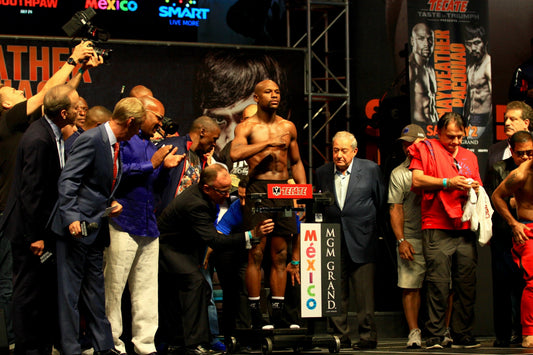 Floyd Mayweather Jr. on stage at the May 2015 boxing weigh-in, shirtless behind the scale