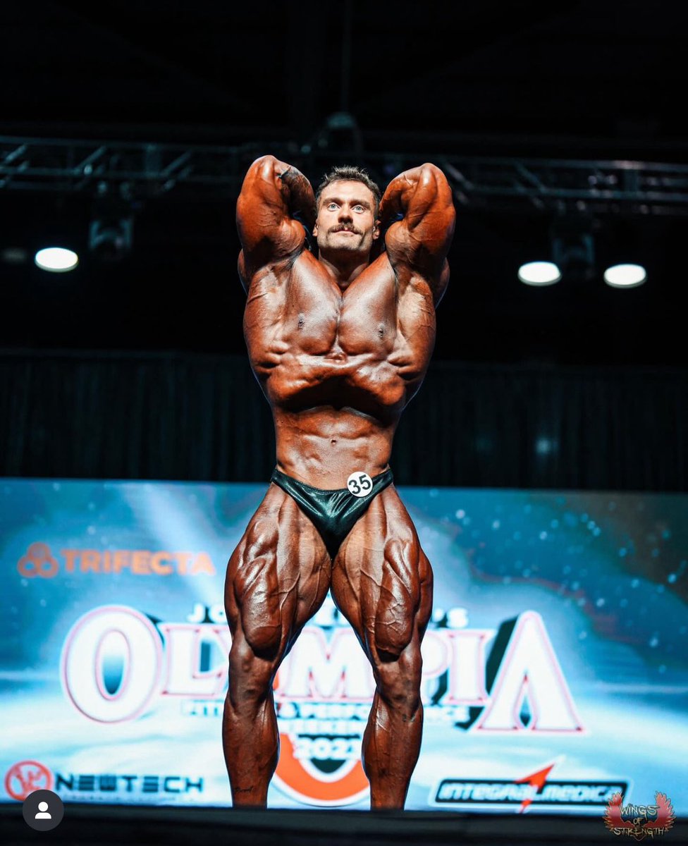 Chris Bumstead performing a classic vacuum pose with a tightly drawn waist on the Olympia stage