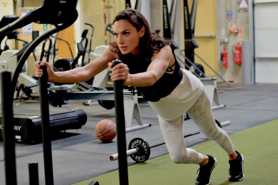 Gal Gadot pushing a weighted sled during athletic training