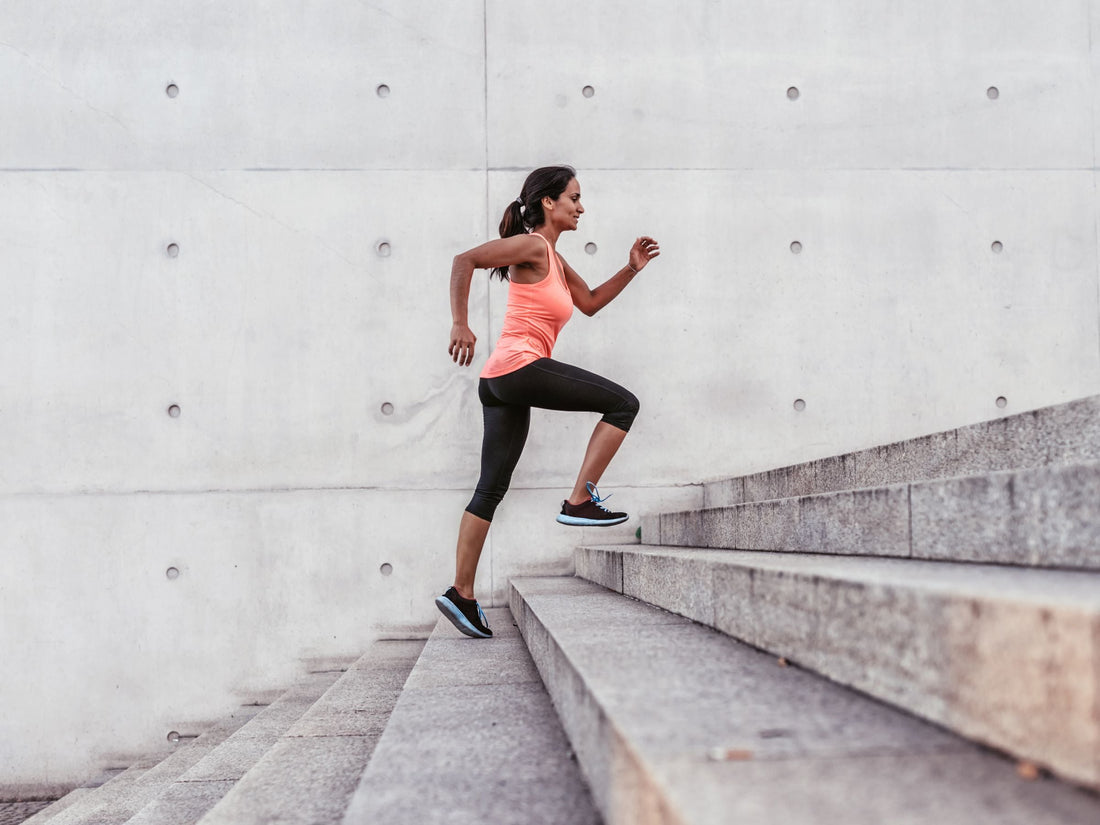 Woman running up wide concrete stairs during an outdoor cardio workout