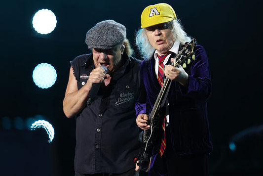 Angus Young playing guitar alongside Brian Johnson onstage during an AC/DC concert