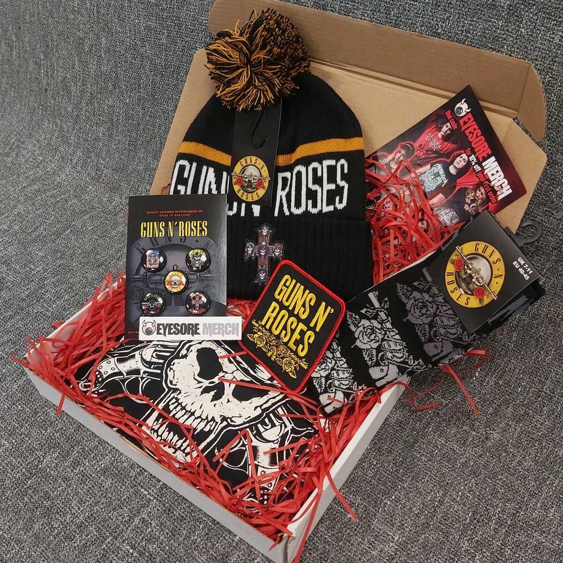 Gift box containing Guns N' Roses-themed black beanie, graphic tee, patches, buttons and rock accessories