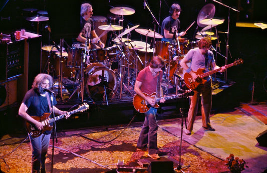 Members of the Grateful Dead playing guitars and drums together onstage at the Warfield Theatre in 1980
