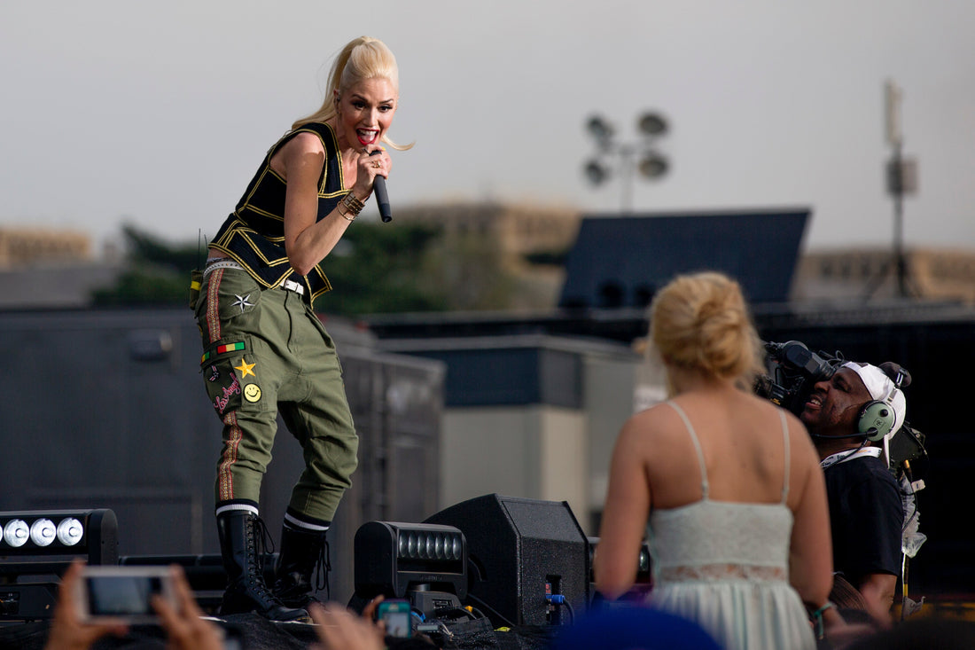 Gwen Stefani singing onstage with No Doubt in an athletic performance pose