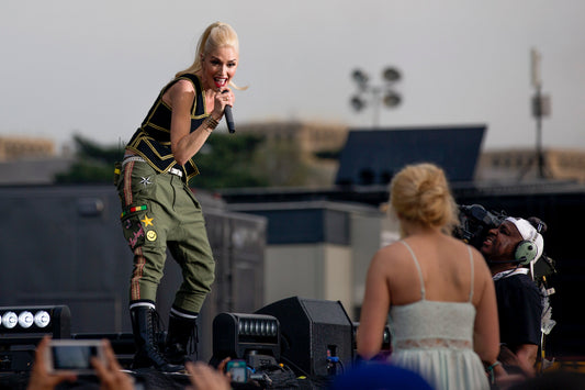 Gwen Stefani singing onstage with No Doubt in an athletic performance pose