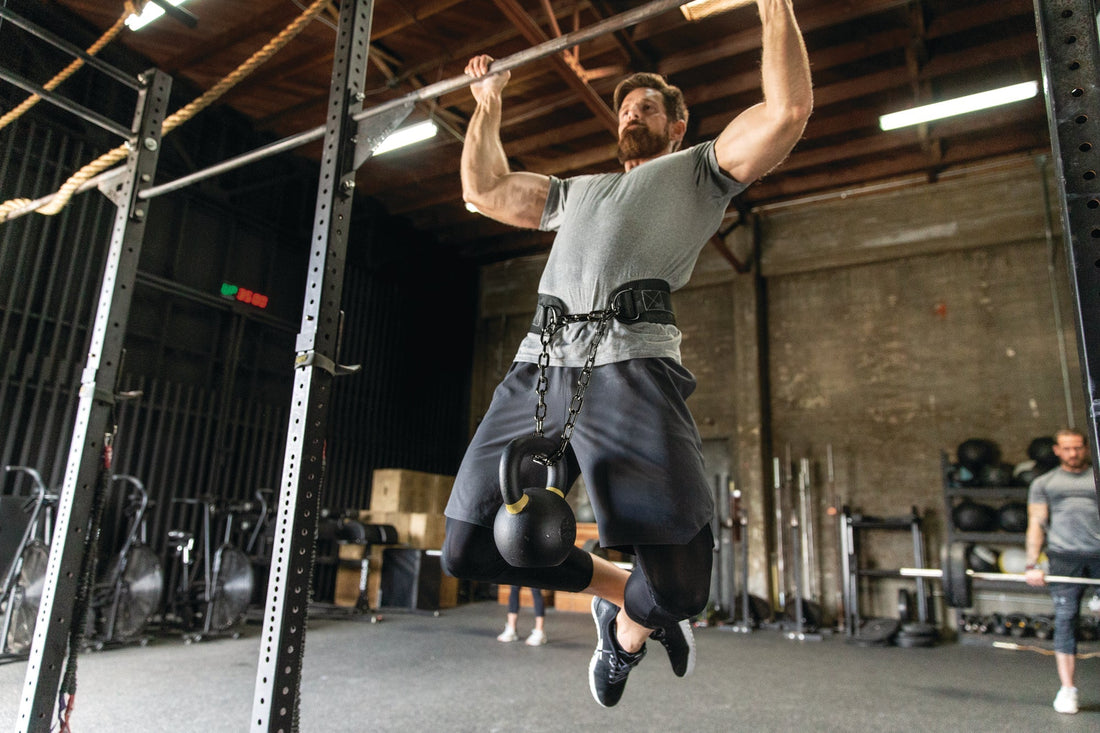 Athlete performing a demanding controlled weighted pull-up on a gym bar