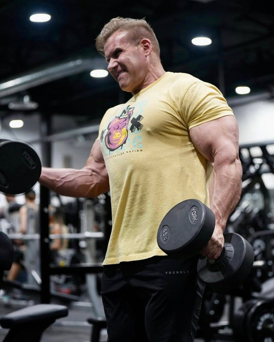 Four-time Mr. Olympia Jay Cutler curling dumbbells in a gym while wearing a yellow T-shirt
