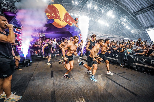 Indoor HYROX competitors launching from the start arch, illustrating the race format debuting in Hungary