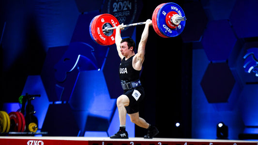 Hampton Morris in a USA weightlifting singlet completing an overhead Olympic lift in competition