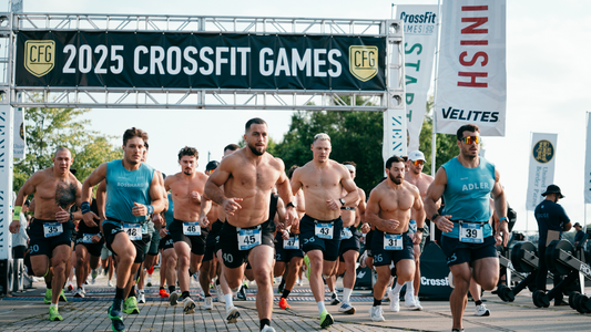 CrossFit competitors sprinting from the Games start line beneath an event banner
