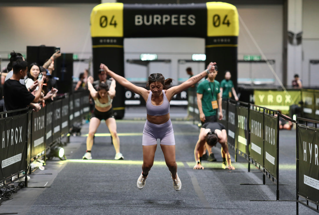 HYROX athlete performing a burpee broad jump in an indoor race lane