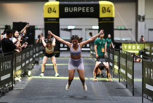 HYROX athlete performing a burpee broad jump in an indoor race lane