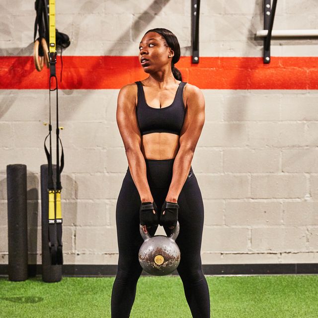 Athlete holding a kettlebell at a gym while bracing the torso for strength training