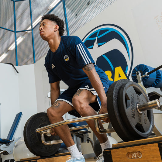 Philadelphia 76ers basketball player lifting a medicine ball overhead in a team weight room