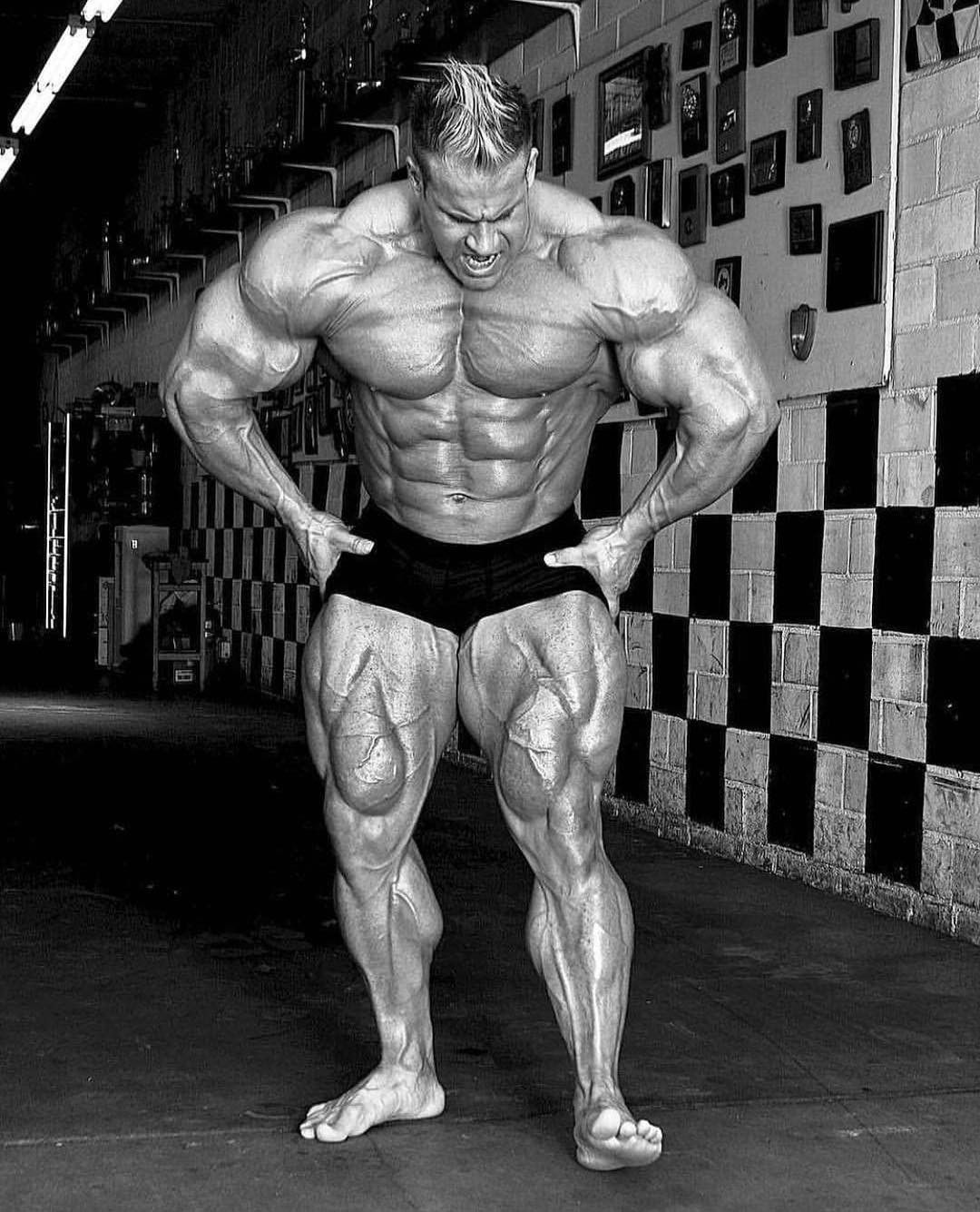 Jay Cutler posing in a gym with defined quadriceps and calves