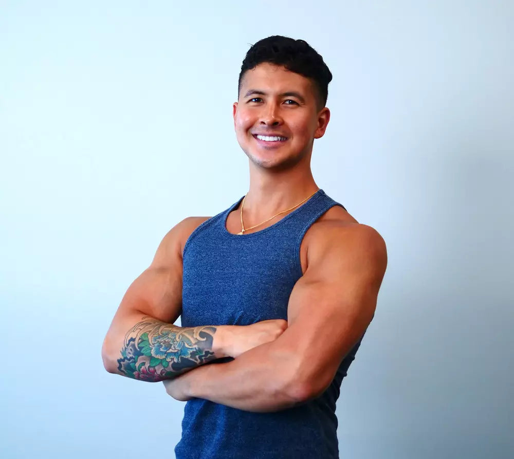 Jeremy Ethier in a blue tank top smiling with his arms folded against a pale background