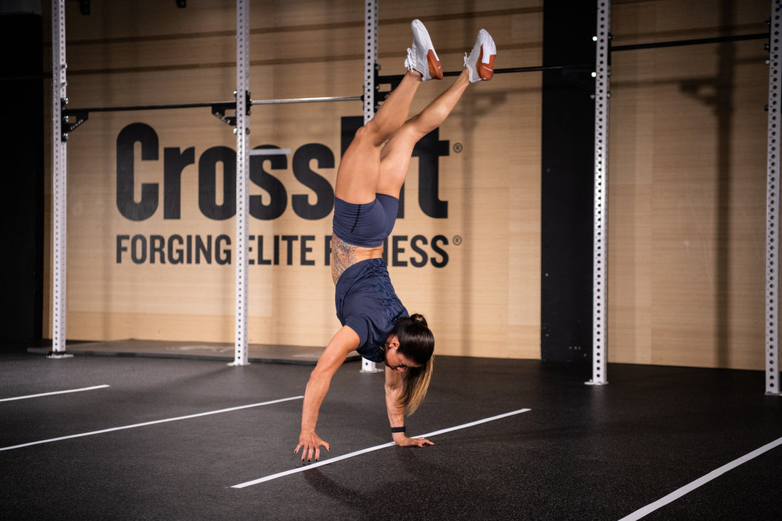 CrossFit athlete walking on her hands between floor markings during a gym workout