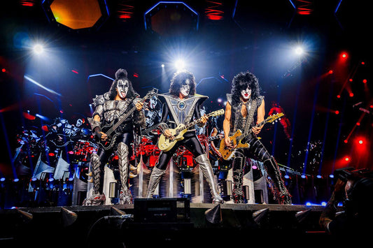 KISS performing live onstage with Gene Simmons, Paul Stanley and other band members playing guitars under bright concert lights