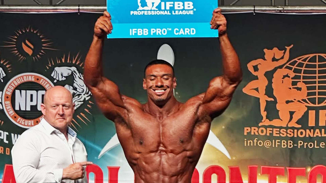 Larry Wheels holds his IFBB Pro card onstage after winning Classic Physique at the 2025 Ireland qualifier