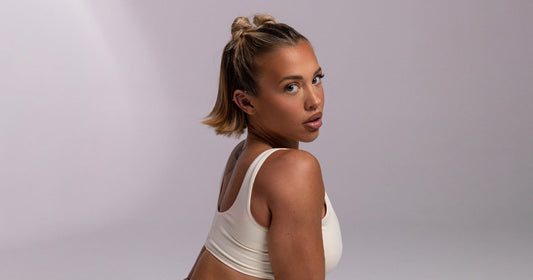 Portrait of Tammy Hembrow wearing white athletic wear and looking over her shoulder