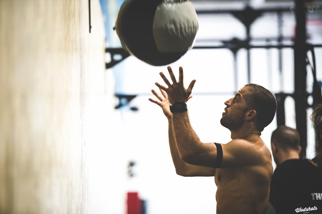 HYROX wall-ball athlete throwing a medicine ball toward a gym target