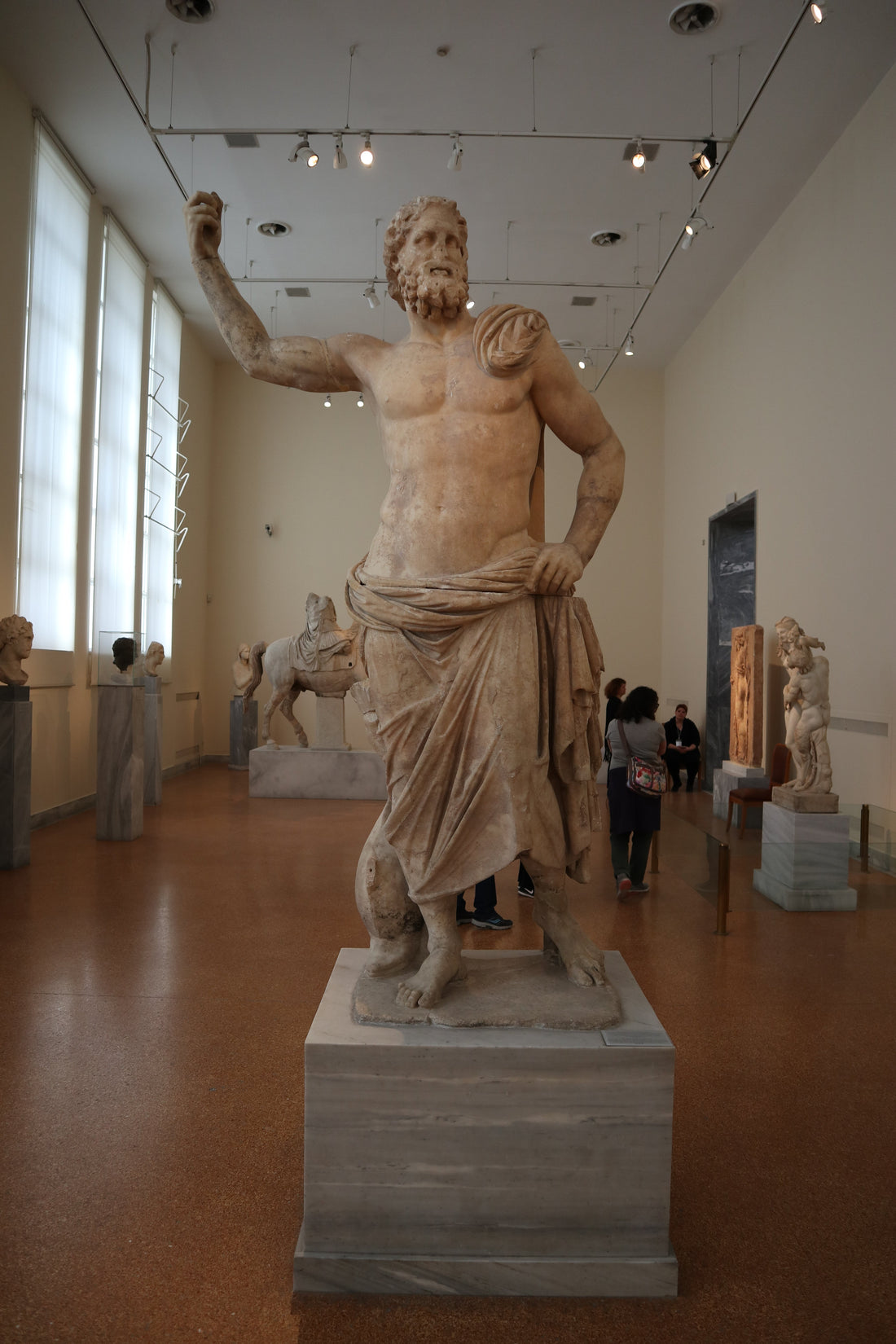 Ancient marble statue of Poseidon of Melos in an Athens museum, illustrating the classical Greek god physique