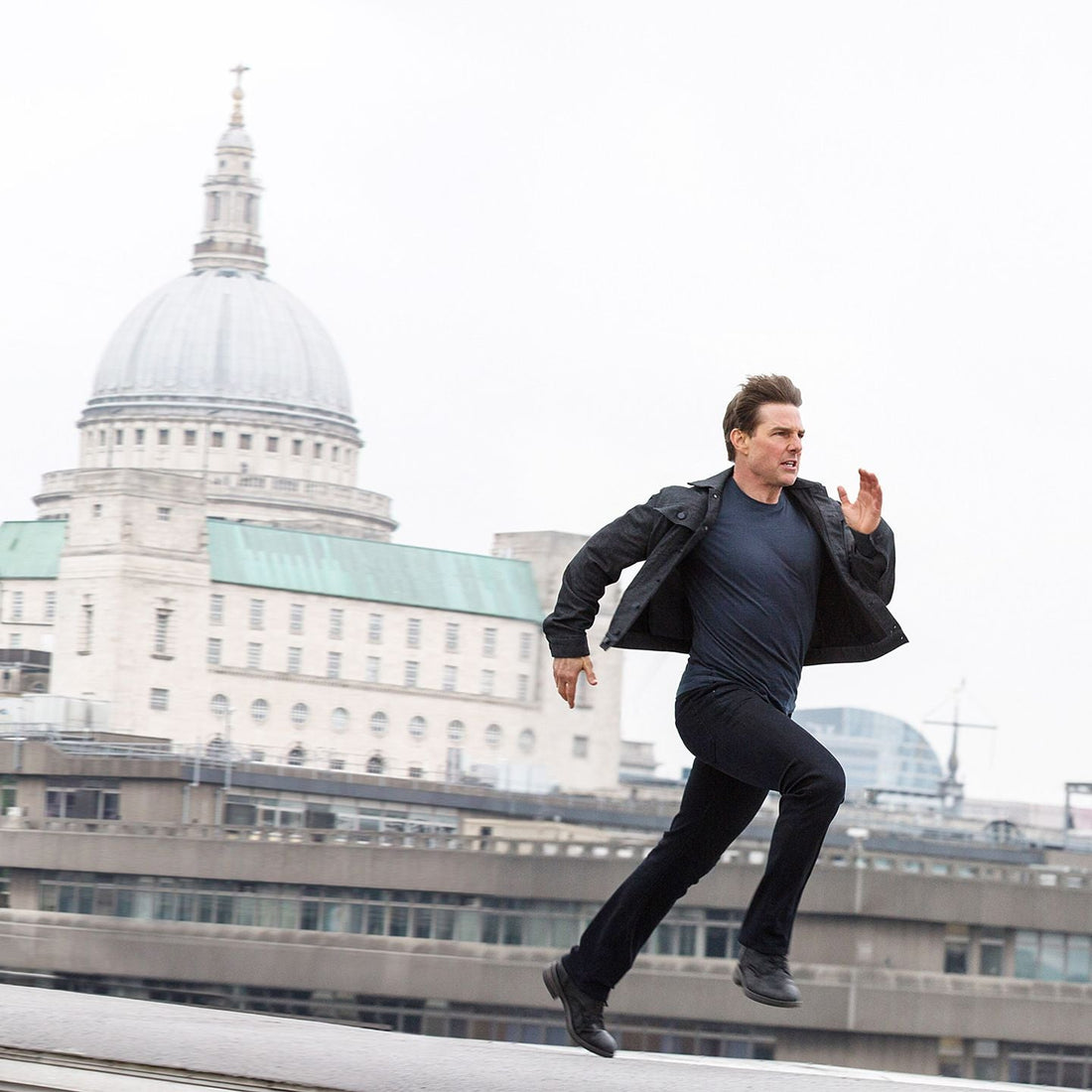 Tom Cruise sprinting across a London rooftop during a Mission Impossible action sequence