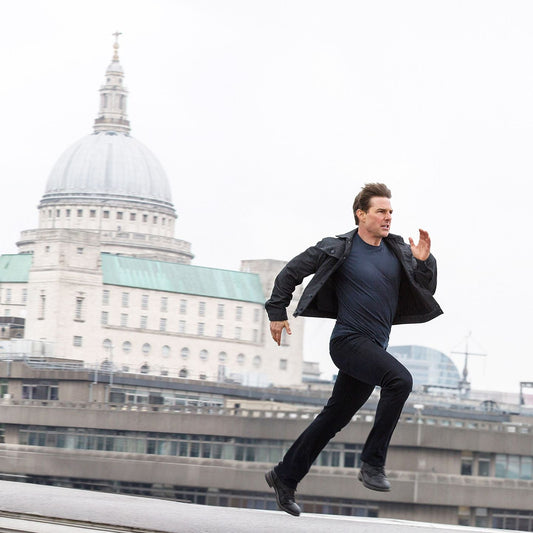 Tom Cruise sprinting across a London rooftop during a Mission Impossible action sequence
