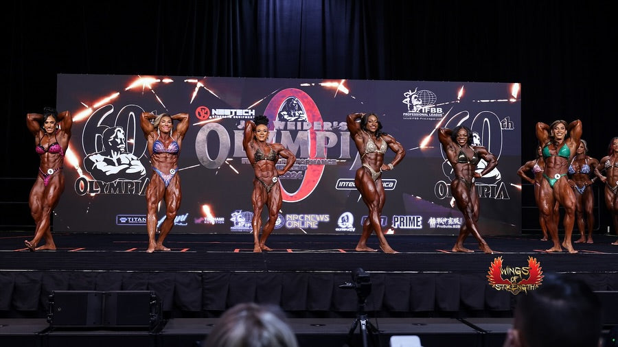 Elite female bodybuilders competing on the Ms. Olympia stage, showing muscular development and symmetry