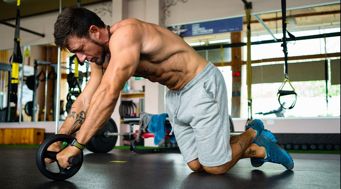 Muscular athlete performing a kneeling ab-wheel rollout on a gym floor