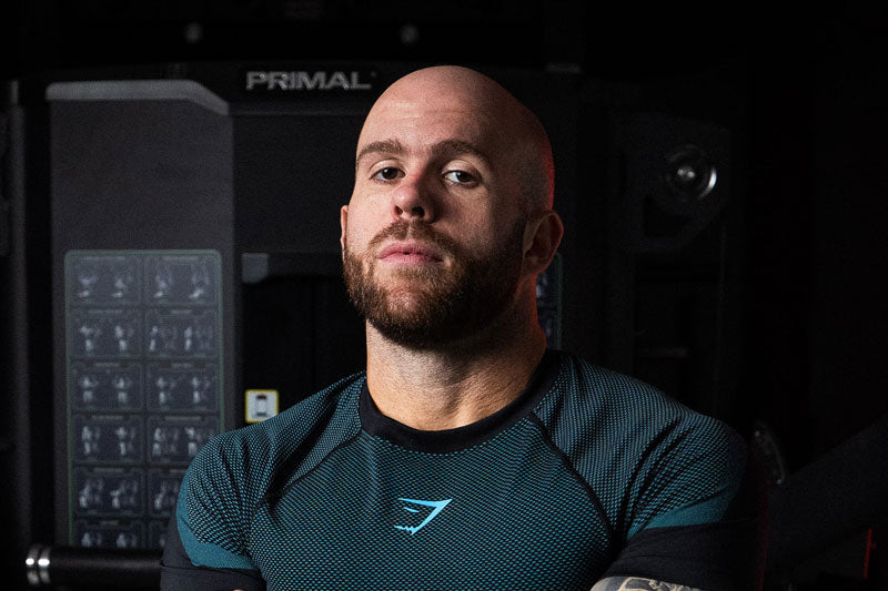 Dr. Pak in a dark athletic shirt standing in front of gym equipment, photographed from the chest up