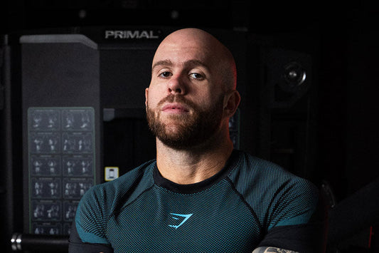 Dr. Pak in a dark athletic shirt standing in front of gym equipment, photographed from the chest up