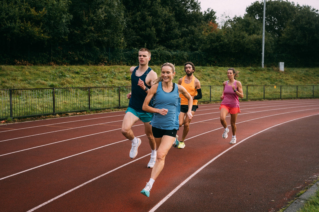 A group of runners training together on a red athletics track