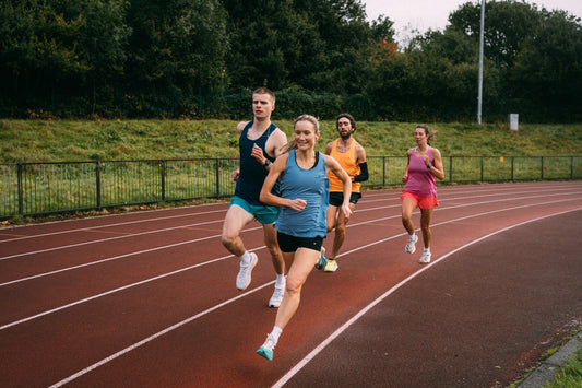A group of runners training together on a red athletics track