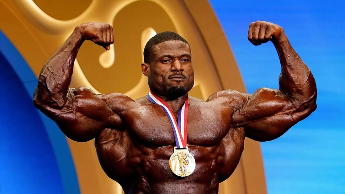 Andrew Jacked front double biceps pose wearing a gold medal onstage at the 2026 Arnold Classic