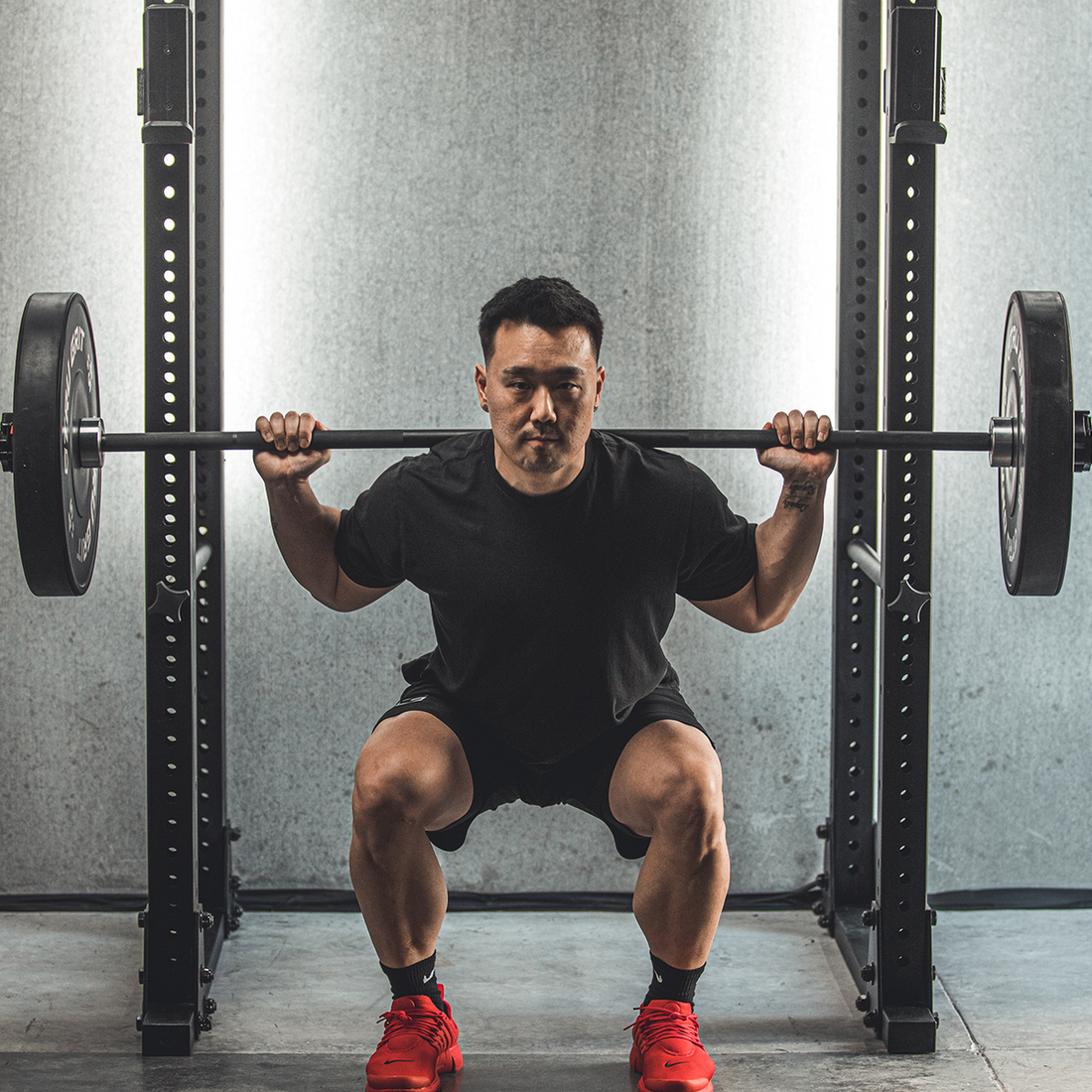 Athlete performing a loaded barbell squat in a power rack