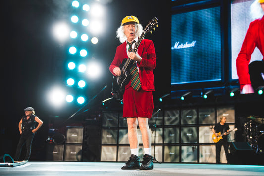 Angus Young performing live with AC/DC during an energetic stadium show