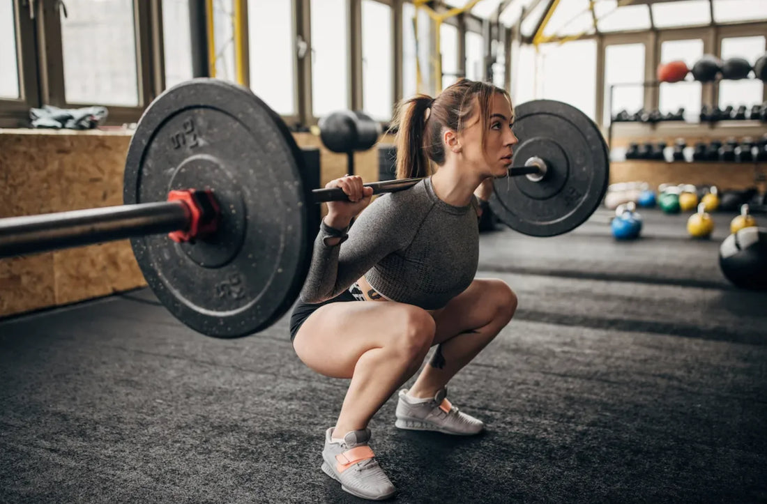 Athlete performing a deep barbell back squat in a gym, demonstrating controlled torso and knee angles
