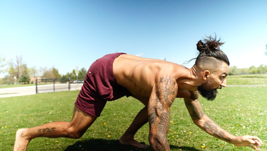 An athlete performing a low quadrupedal primal movement crawl outdoors