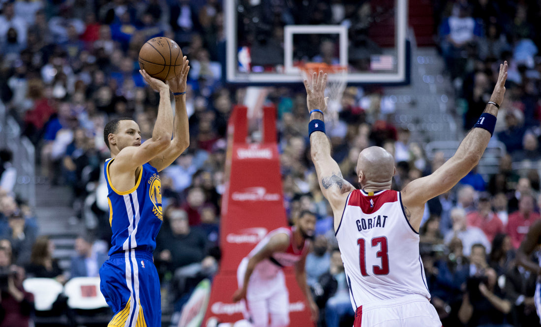 Stephen Curry taking a jump shot for the Golden State Warriors, representing an NBA rumors roundup led by his extension choices and Domantas Sabonis trade news.