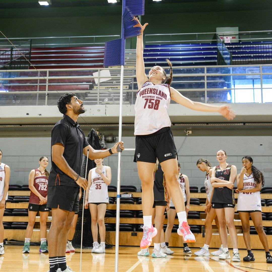 Athlete leaping toward a vertical-jump measurement device during performance testing