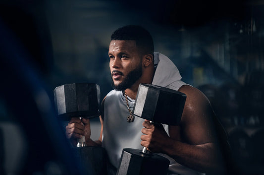 Aaron Donald holding two heavy dumbbells during a focused gym training session