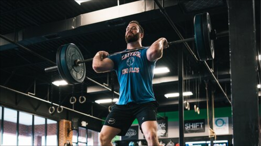 An athlete receiving a barbell hang power clean at shoulder height in a functional fitness gym