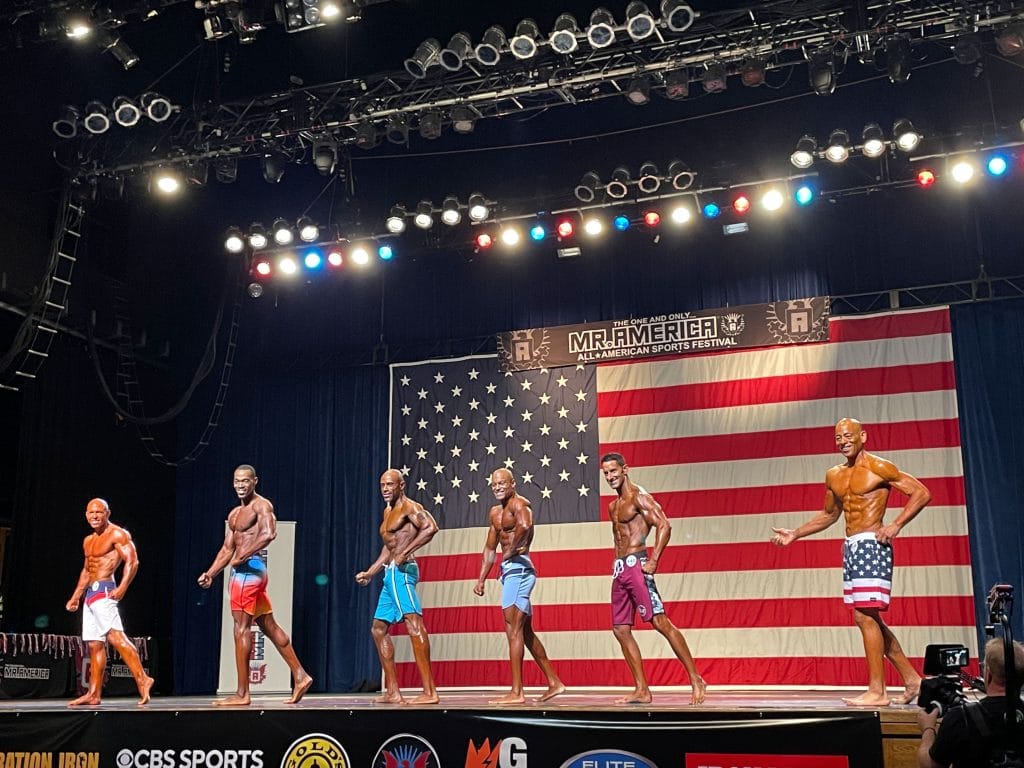 Male physique competitors posing onstage at an earlier Mr America All-American Sports Festival