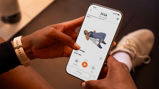 Hands holding a smartphone displaying a guided strength exercise animation in the Strava app