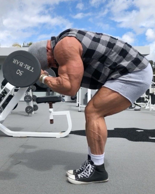 Joey Swoll flexing his muscular arms in a gym