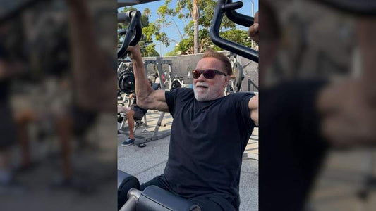 Arnold Schwarzenegger performing a seated upper-body machine exercise outdoors at age 79