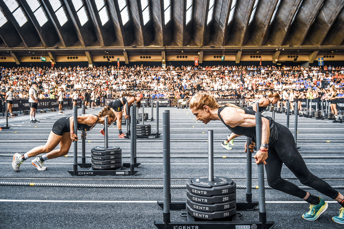 HYROX competitors pushing weighted sleds in an indoor race arena